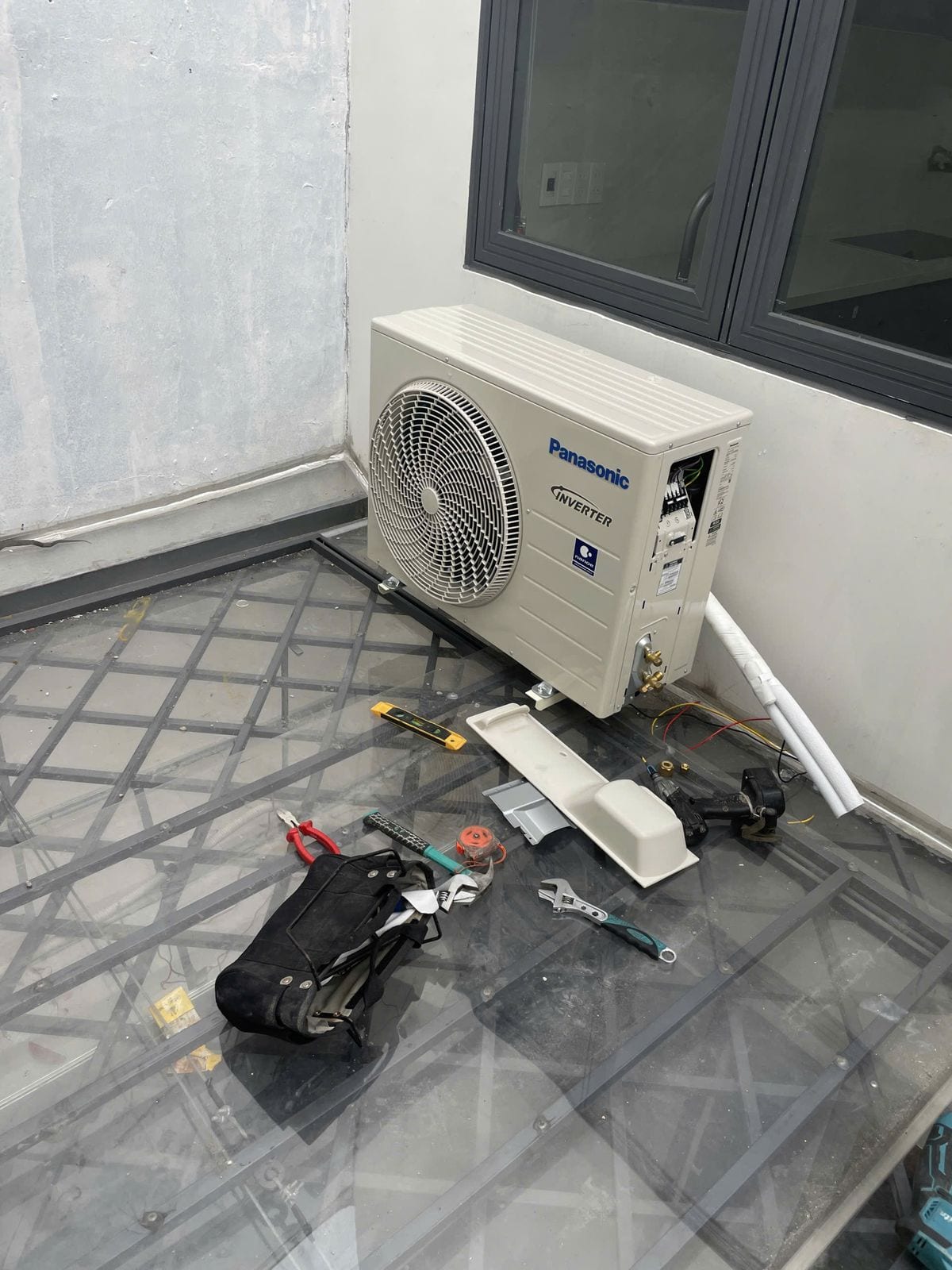Dàn nóng máy lạnh Panasonic Inverter vừa lắp xong trên sàn kỹ thuật, dụng cụ thợ bên cạnh