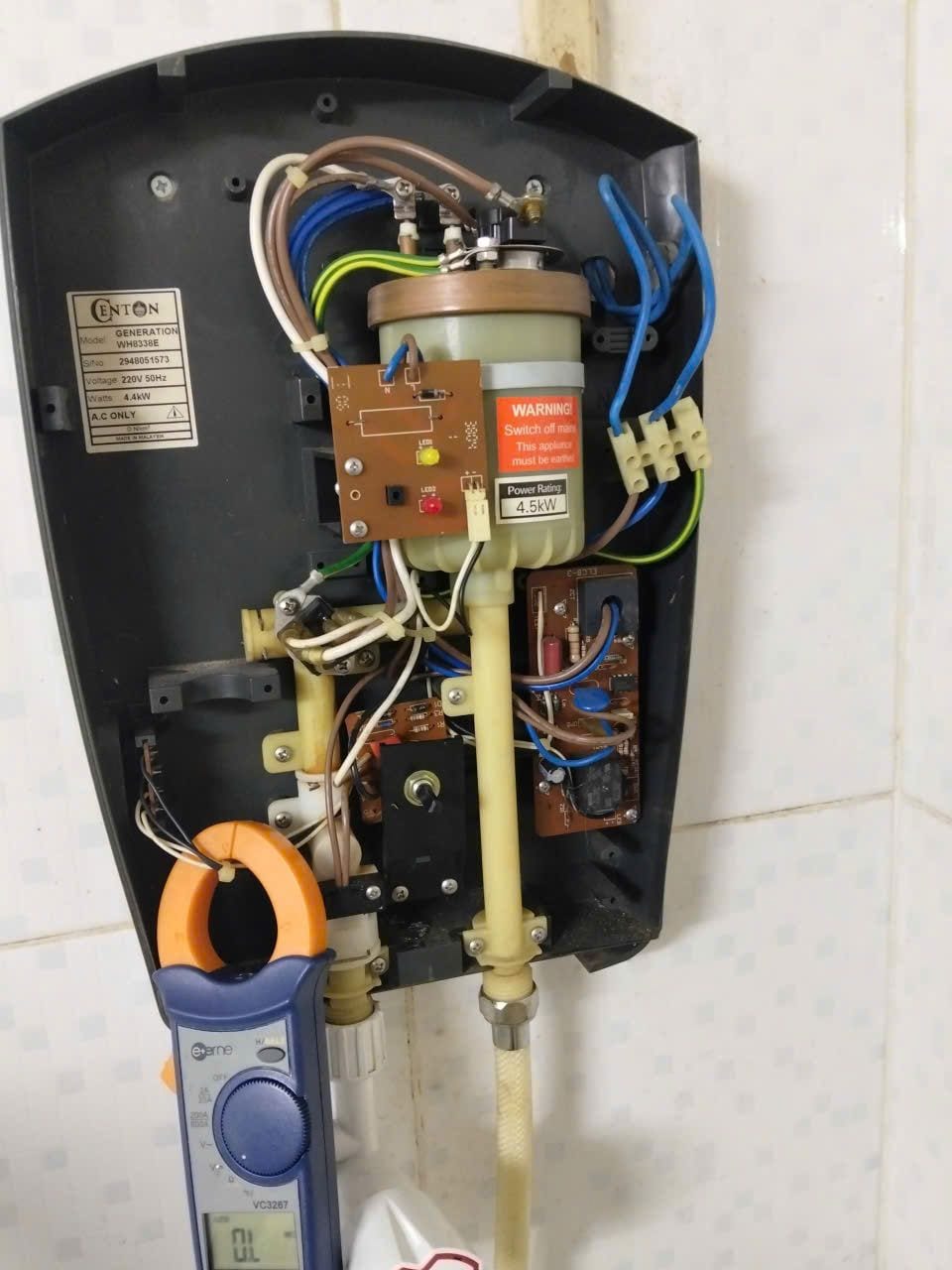 Máy nước nóng trực tiếp Centon đã tháo nắp, thợ đo dòng điện bằng ampe kìm